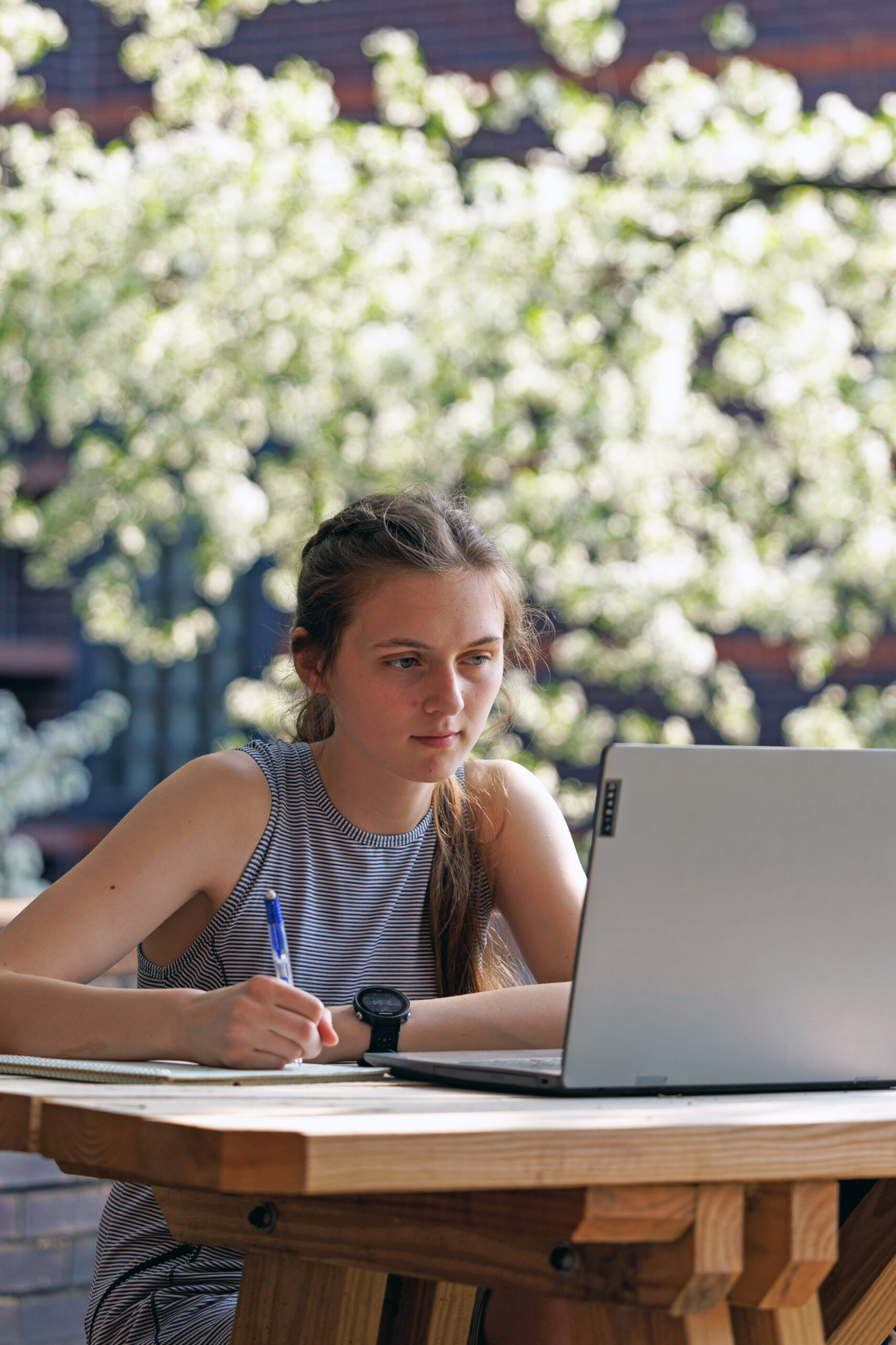 Elizabeth (Belling) Krigbaum studying in Black Engineering courtyard with flowering trees.